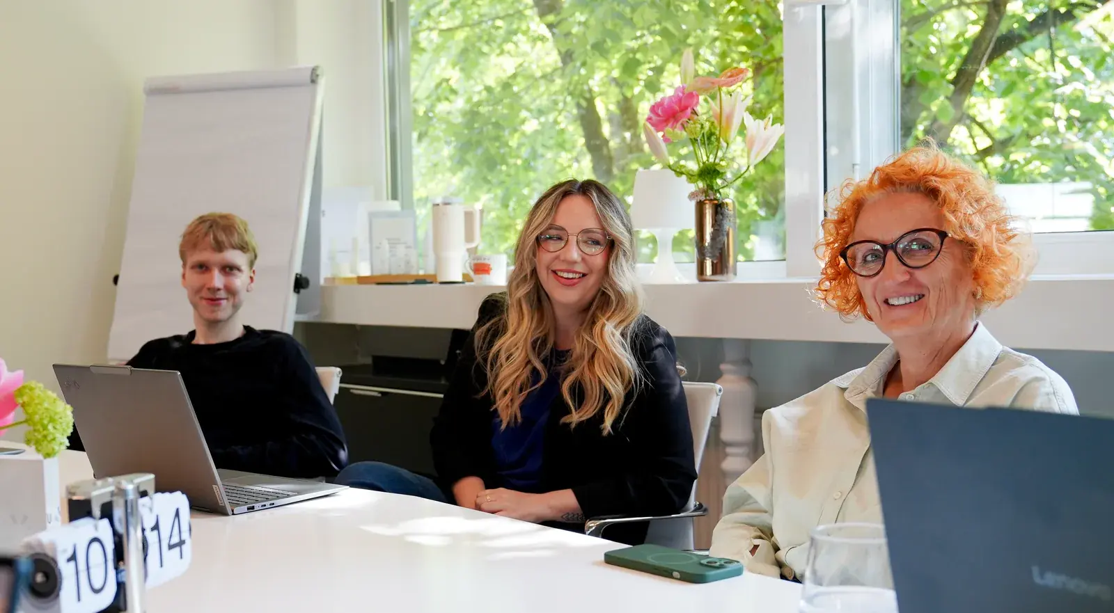 Members of the USP Demo Solutions team smiling together around a meeting table in the Klagenfurt office